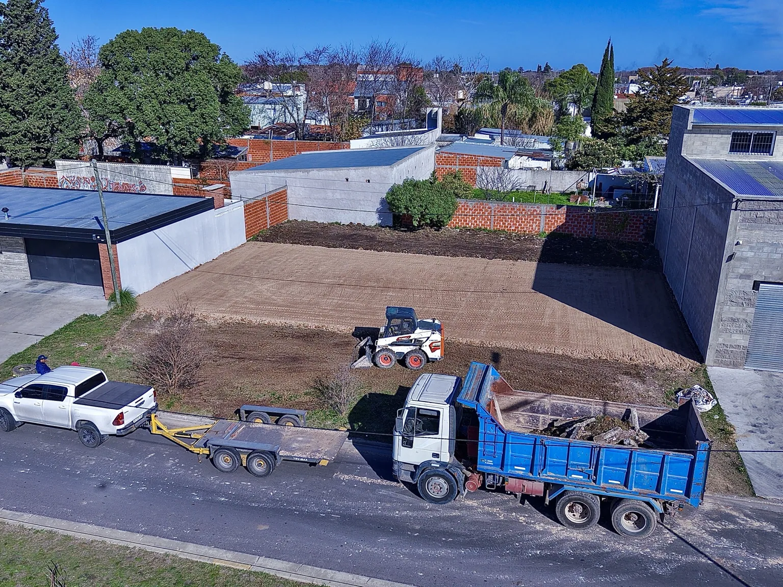 Bobcat y camión de Movimiento de Suelo JL trabajando en la preparación de un terreno